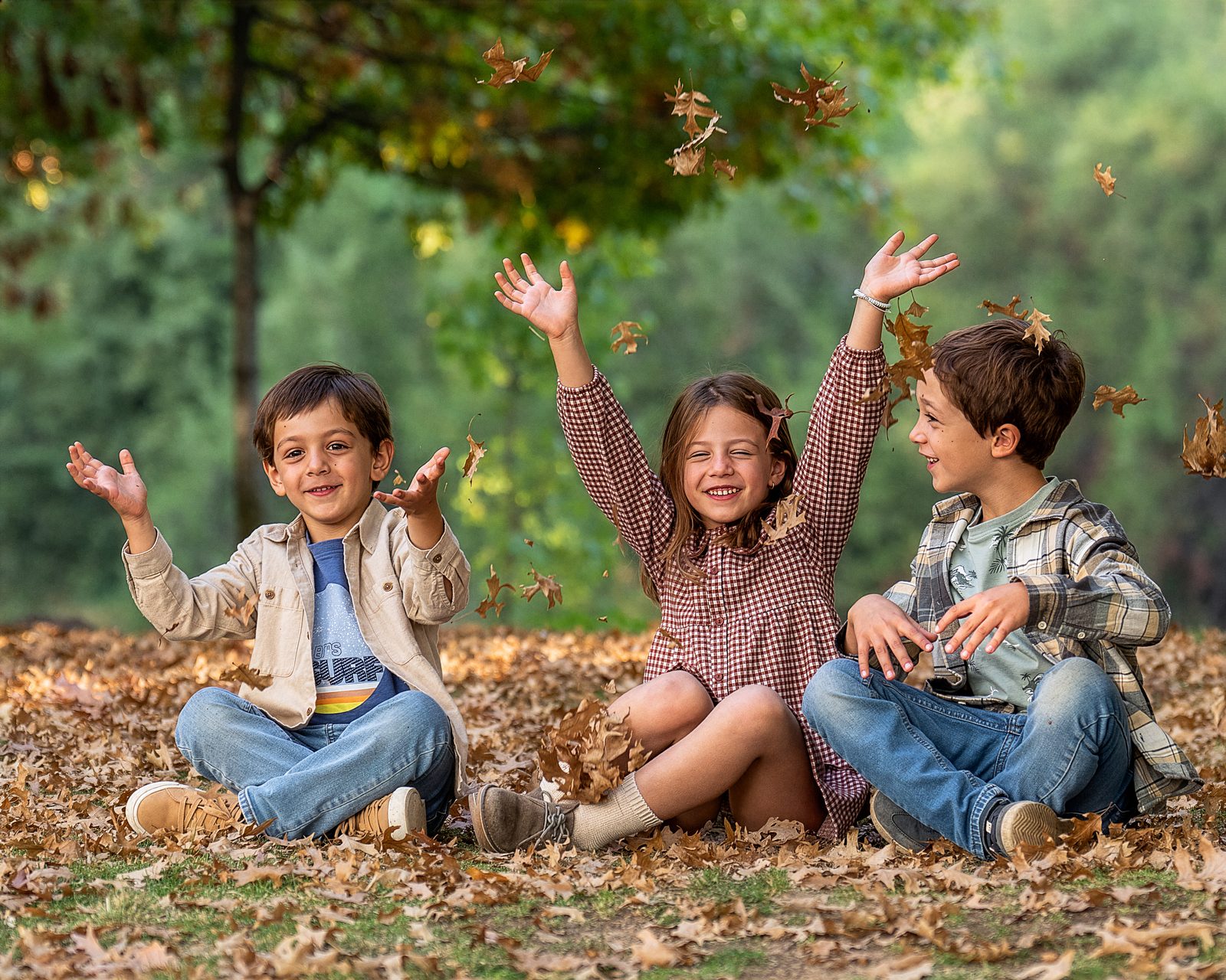 Tres niños jugando con hojas de otoño